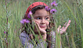 young girl in a field of tall grasses and wildflowers